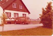 Rotes Lieferfahrzeug vor einem Wohnhaus geparkt.