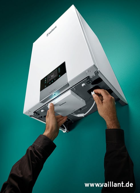 Techniker wartet moderne Vaillant Heiztherme an der Wand